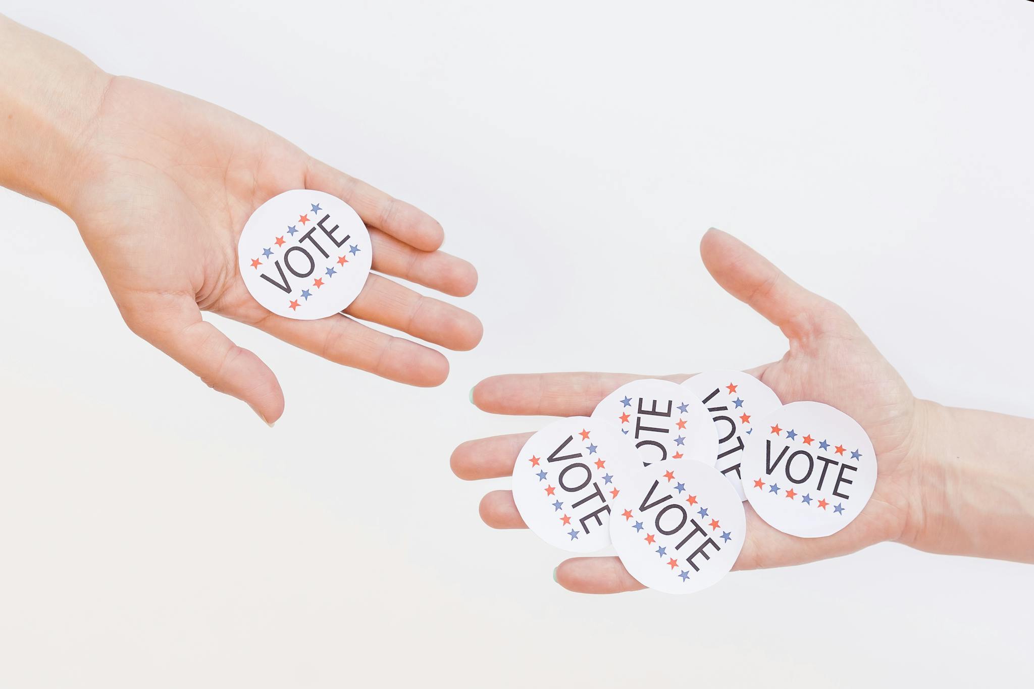 Close-up of hands holding election vote stickers, symbolizing participation.